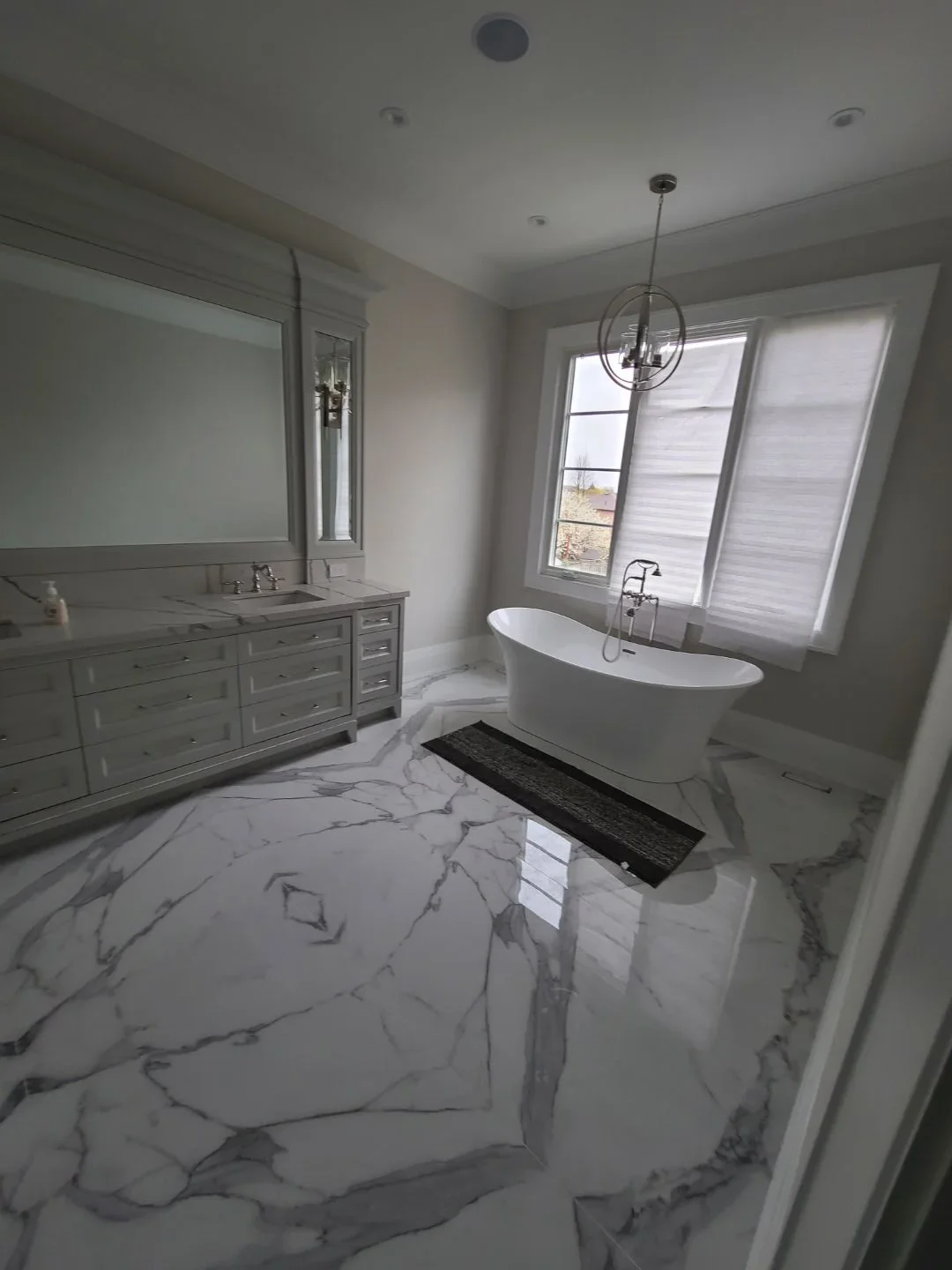bathroom renovation in Toronto by Affordabuild. Marble tiles, bathtub, his and hers vanity, and shower.